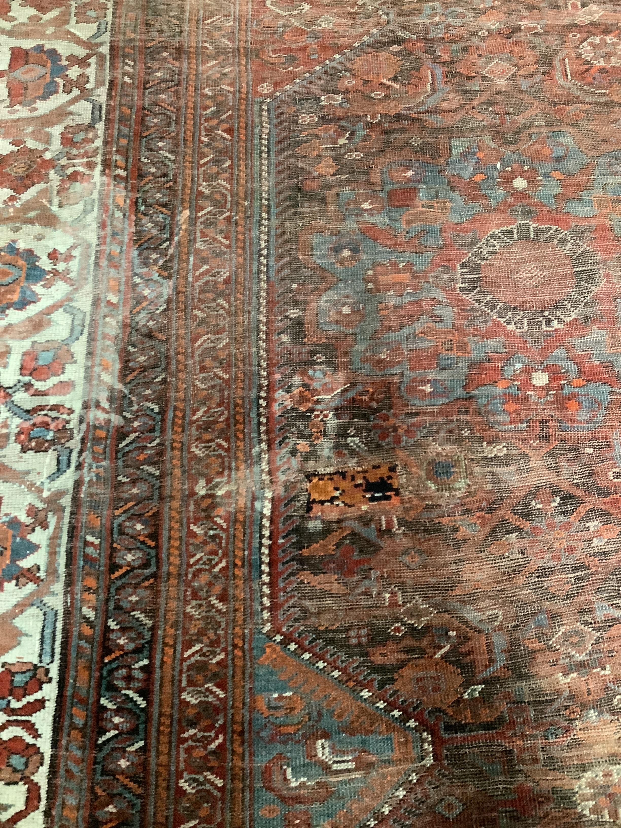 An early 20th century North West Persian red ground carpet, 410 x 348cm, worn and patch repaired.